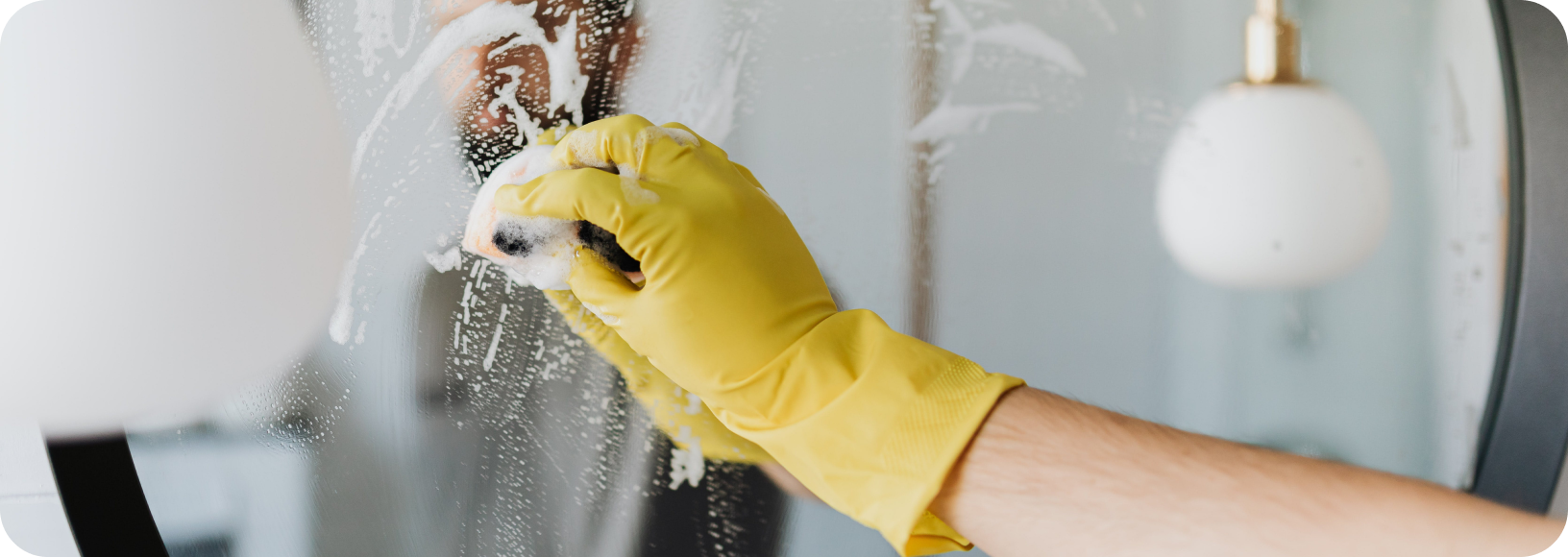 hand with yellow glove wiping mirror